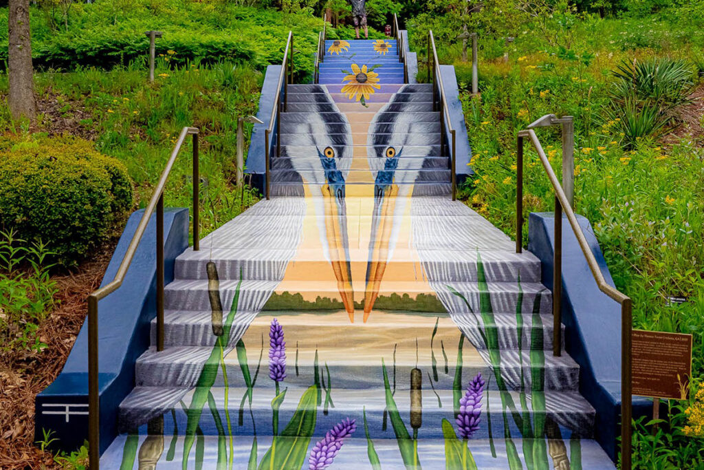 A colorful mural depicting a pair of Great Blue Herons in a wetland welcomes you up the stairs at the Chattahoochee Nature Center