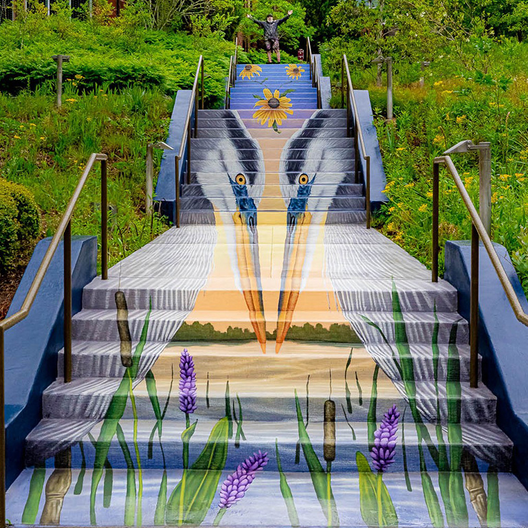A colorful mural depicting a pair of Great Blue Herons in a wetland welcomes you up the stairs at the Chattahoochee Nature Center